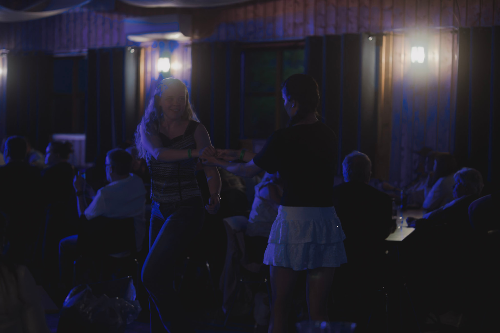 To kvinner danser på dansegulvet i blått scenelys