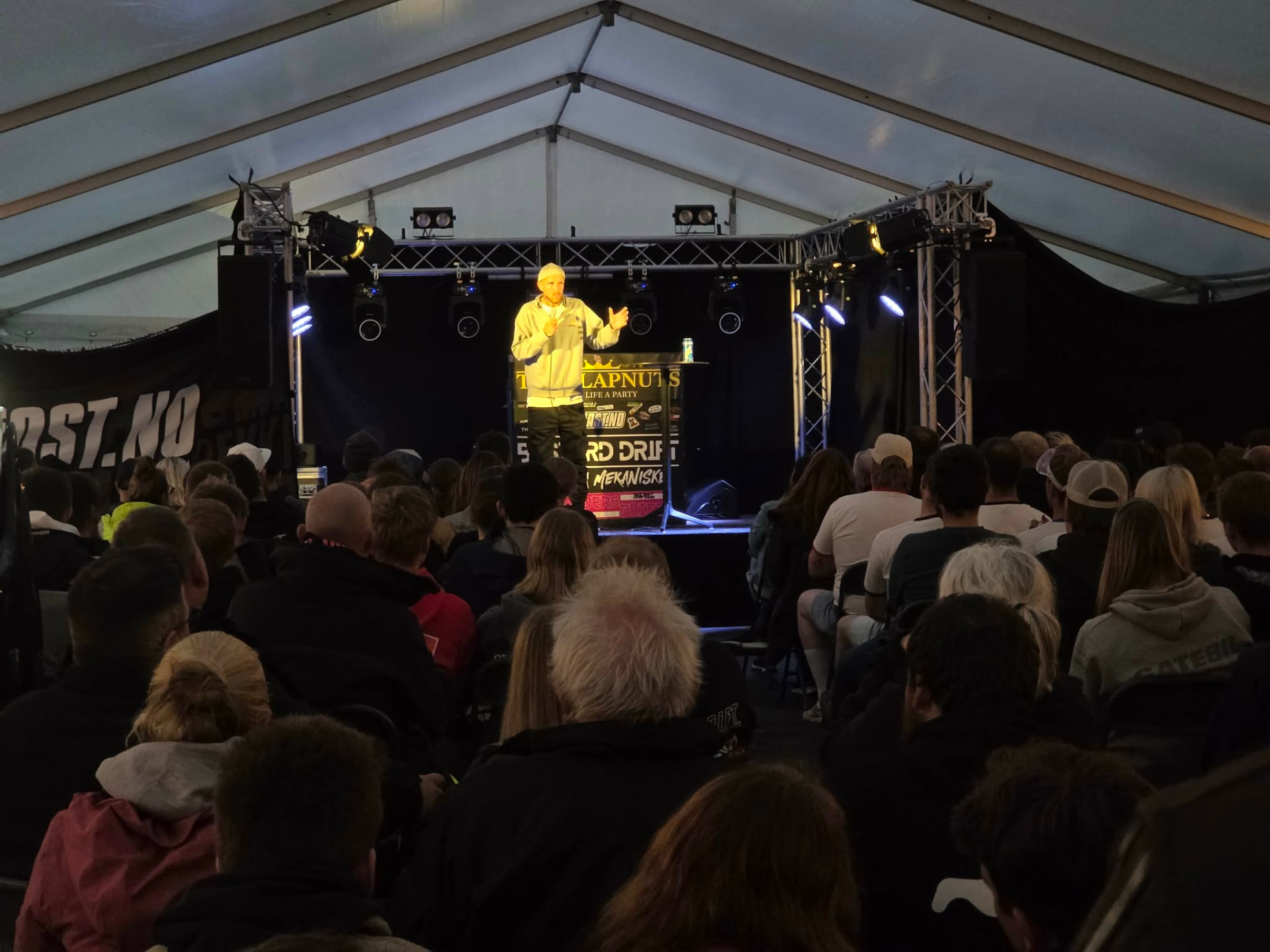 Komiker på scenen i telt foran fullsatt publikum