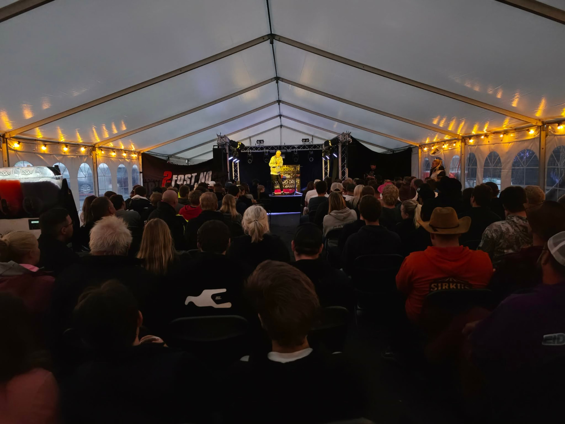 Stort festtelt fylt av publikum foran scenen